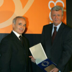 Ï Ðáíáãéþôçò Íßêáò (Ä) (åðßôéìïò Ðñüåäñïò ôïõ ÓÅÂÅÊ) ðáñáëáìâÜíåé ôçí ôéìçôéêÞ ðëáêÝôá áðü ôïí ÁëÝîç ÕöáíôÞ (Á) Ðñüåäñï ôïõ ÓÅÂÅÊ (Óýíäåóìïò Åëëçíéêþí Âéïìç÷áíéþí Åðåîåñãáóßáò ÊñÝáôïò) Ôñßôç 02 Íïåìâñßïõ 2004. Ç åêäÞëùóç Ýãéíå óôï ðëáßóéï çìåñßäáò ðïõ äéïñãÜíùóå ï ÓÅÂÅÊ ìå èÝìá «Áðü ôïí ×áñßíï óôï åðþíõìï Áëëáíôéêü